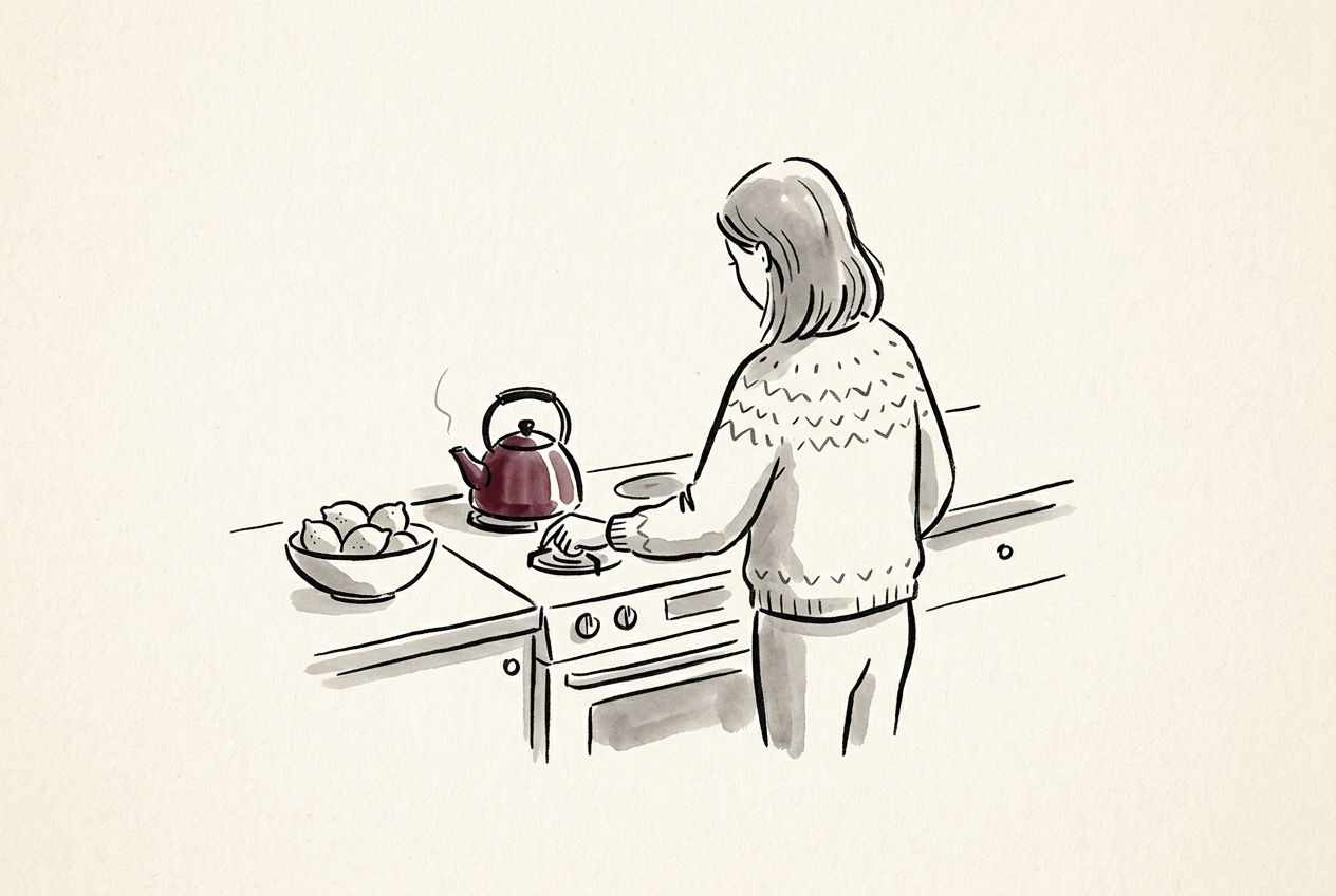 A small kitchen in soft morning light, a woman seen from behind reaching to turn off the burner under a kettle, a bowl of lemons on the counter beside her; the maroon touch is on the kettle.