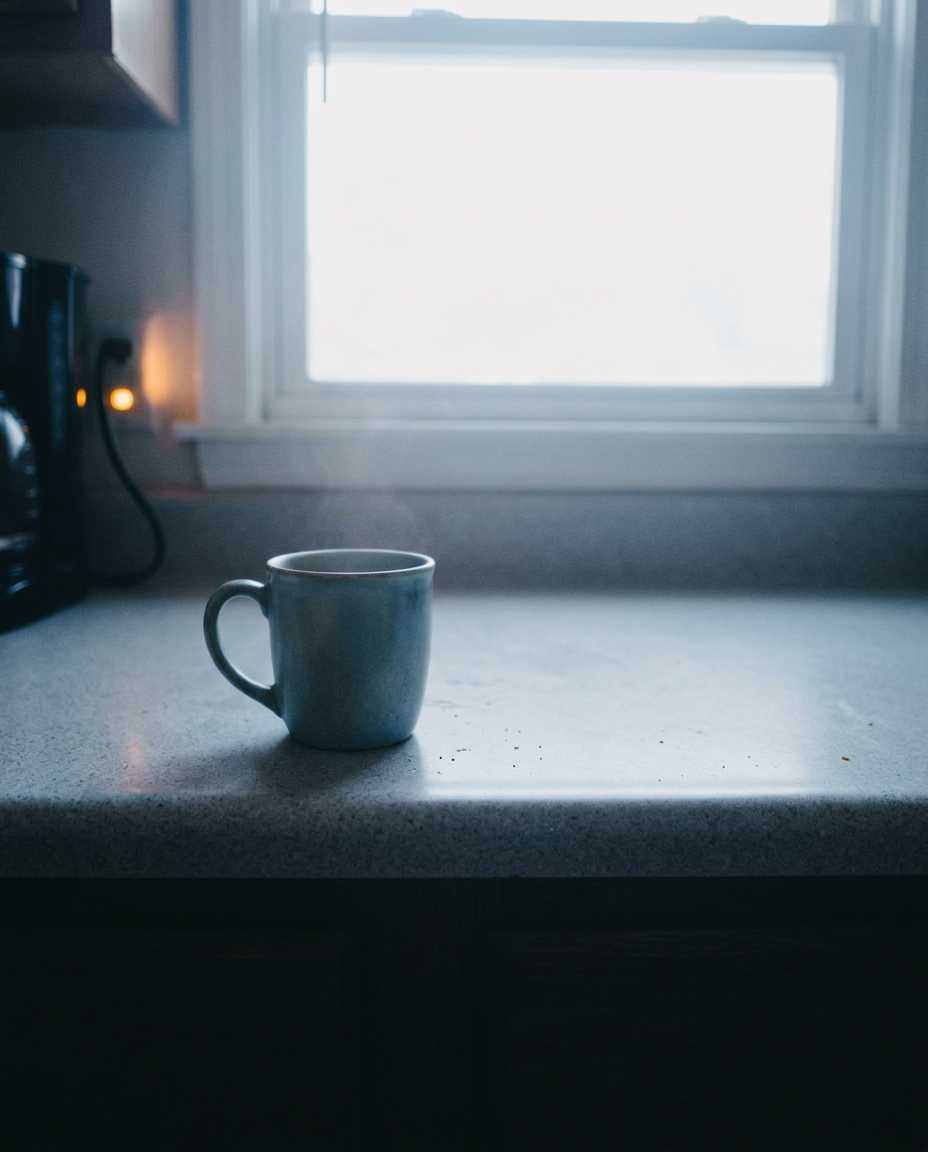 Cold morning light on a kitchen counter, one mug, nothing staged